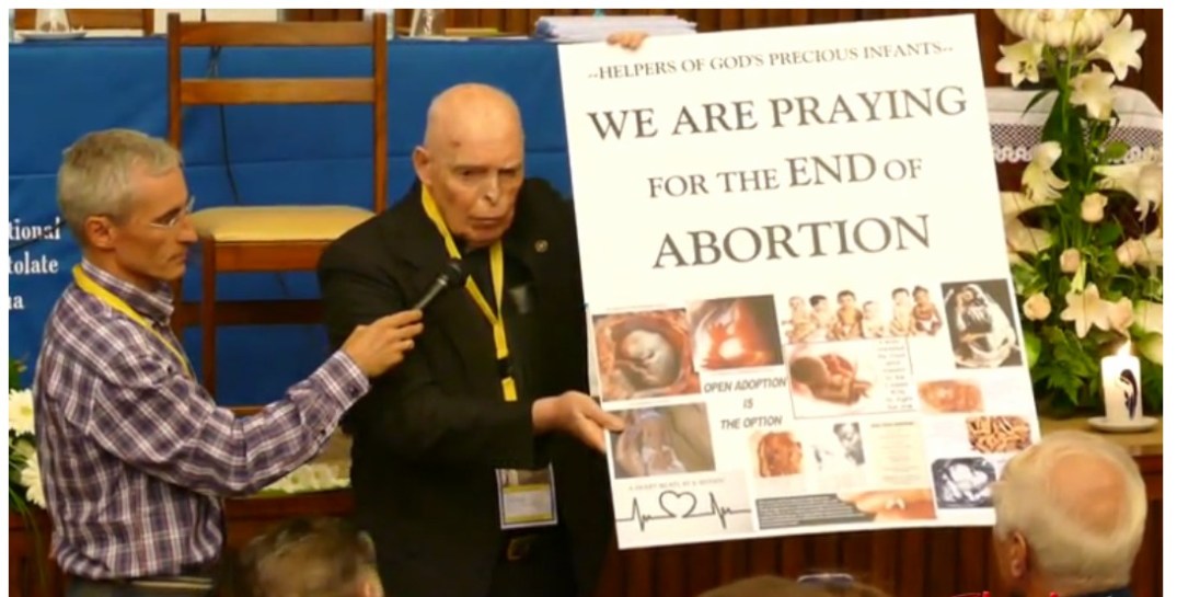 monsignor holding poster